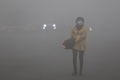 スモッグに覆われた中国東北部・黒竜江（Heilongjiang）省ハルビン（Harbin）で、マスクを着用して歩く女性（2013年10月21日撮影）。(c)AFP