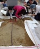 ドイツ考古学協会（German Archaeological Institute）の北京（Beijing）事務所が公開した、中国・新疆ウイグル自治区（Xinjiang Uighur Autonomous Region）で発見された衣服を調べる科学者たち（2014年2月8日撮影、2014年6月6日公開）。(c)AFP/GERMAN ARCHAEOLOGICAL INSTITUTE PEKING