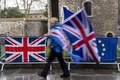 英国の首都ロンドンの下院近くで、英国旗（左）と欧州連合（EU）旗の前を通る人（2019年3月18日撮影）。(c)Niklas HALLE&apos;N / AFP