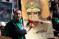 リビアの首都トリポリ（Tripoli）で行われた最高指導者ムアマル・カダフィ（Moamer Kadhafi）大佐を支持する集会で、大佐の写真に花を捧げる参加者（2011年2月16日撮影）。(c)AFP/MAHMUD TURKIA