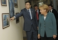 グルジアの首都トビリシ（Tbilisi）の大統領官邸で、訪問中のドイツのアンゲラ・メルケル（Angela Merkel）首相（右）に壁に飾った絵画の説明をするグルジアのミハイル・サーカシビリ（Mikhail Saakashvili）大統領（左、2008年8月17日撮影）。(c)AFP/DPP/MICHAEL GOTTSCHALK