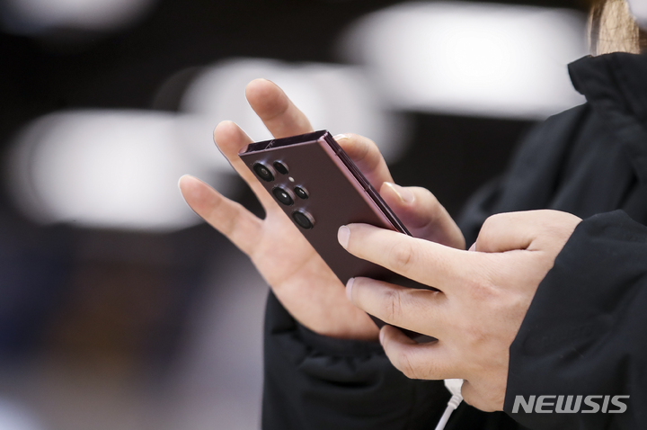 スマートフォンを見る市民(c)NEWSIS