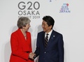 大阪で開催中の20か国・地域（G20）首脳会議の歓迎行事で、テリーザ・メイ英首相（左）を迎える安倍晋三首相（右、2019年6月28日撮影）。(c)KIM KYUNG-HOON / various sources / AFP
