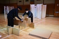坂茂氏が設計した、主にネットカフェを拠点としていた人々を受け入れるための間仕切りやベッドを組み立てる人々。神奈川県横浜市の県立武道館で（2020年4月14日撮影）。(c)CHARLY TRIBALLEAU / AFP