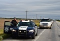 メキシコ北東部タマウリパス州で、ギャングが横行する高速道路101号線を連邦警察のパトカーに先導されて走る一般車両（2015年12月16日撮影）。(c)AFP/RONALDO SCHEMIDT