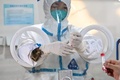 中国・上海の静安区で、住民から検体を採取する医療従事者が身に着けた防護服の袖口から顔をのぞかせるネコ（2022年6月6日撮影）。(c)Hector RETAMAL / AFP