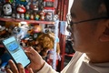 2024年パリ五輪のグッズをスマートフォンで見るチャン・ウェンチュワンさん。中国・北京の自宅で（2021年12月30日撮影）。(c)Jade GAO / AFP