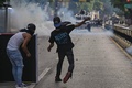 ベネズエラの首都カラカスで、ニコラス・マドゥロ大統領の再選結果に抗議し、警察官に投石するデモ参加者（2024年7月29日撮影）。(c)Yuri CORTEZ / AFP