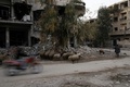 シリアの首都ダマスカス近郊ジョバルで、損壊した建物の近くで羊に草を食べさせる男性（2016年2月24日撮影）。(c)AFP/ABDULMONAM EASSA