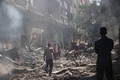 イスラエル軍による人質救出作戦で損傷した建物と散乱したがれきの中を移動する人々。パレスチナ自治区ガザ地区中部ヌセイラット避難民キャンプで（2024年6月8日撮影）。(c)EYAD BABA / AFP