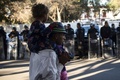 メキシコ北部ティフアナで、警備に当たる警察官らのそばを歩く中米からの移民親子（2018年11月26日撮影）。(c)Guillermo Arias / AFP