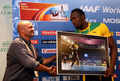 第14回世界陸上モスクワ大会（14th IAAF World Championships in Athletics Moscow）男子100メートル決勝で撮影された写真を受け取り、撮影者のオリビエ・モラン（Olivier Morin、左）氏と握手を交わすウサイン・ボルト（Usain Bolt、2013年8月17日撮影）。(c)AFP/FRANCK FIFE