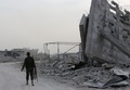 シリア首都ダマスカス近郊東グータに入り、破壊された建物の横を歩く政府軍の兵士（2018年3月4日撮影）。(c)AFP