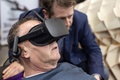オランダのアムステルダムで開催された葬儀関連の見本市で、VR（仮想現実）ゴーグルを装着して自殺機器「サルコ」を体験する男性に機能を説明する、デザイナーのアレクサンダー・バニンク氏（2018年4月14日撮影）。(c)AFP/ANP/Jasper Juinen