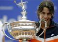男子テニス、バルセロナ・オープン・バンコ・サバデル（%%Barcelona Open Banco Sabadell 2009%%）シングルス決勝。大会第1シードのラファエル・ナダル（%%Rafael Nadal%%、スペイン）は、大会第4シードのダビド・フェレール（%%David Ferrer%%、スペイン）と対戦。ナダルはセットカウント2-0（6-2、7-5）のストレートで勝利し、大会5連覇を達成した。写真は優勝を果たし、トロフィーをかむラファエル・ナダル。（2009年4月26日撮影）(c)AFP/JOSEP LAGO