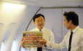 タイのバンコク（Bangkok）に向かう機内で、新聞記事を掲げるタクシン・シナワット（Thaksin Shinawatra）元首相。(c)AFP/MIKE CLARKE