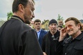 ウクライナの首都キーウ近郊ブチャで集団埋葬地を訪れたロックバンド「U2」のボノさん（右）とジ・エッジさん（右から2人目）を案内する教会の神父（2022年5月8日撮影）。(c)Genya SAVILOV / AFP