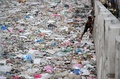 フィリピンの首都マニラで、ごみのあふれる川に下りる男性（2016年1月23日撮影）。(c)AFP/NOEL CELIS