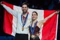 フィギュアスケート世界選手権、ペア・フリースケーティング（FS）。優勝を飾り、表彰式で国旗を掲げるカナダのディアナ・ステラト・ドゥデク/マキシム・デシャン組（2024年3月21日撮影）。(c)Geoff Robins / AFP