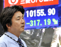 都内で、株価を示す電光ボードの前を通る男性（2008年10月7日撮影）。(c)AFP/Yoshikazu TSUNO