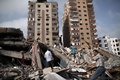 パレスチナ自治区ガザ地区（Gaza Strip）ガザ市（Gaza City）で、ミサイル着弾で倒壊した集合住宅のがれきの中に私物がないか調べる人々（2014年8月24日撮影）。(c)AFP/THOMAS COEX