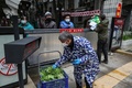 中国中部・湖北省武漢で、ゲート越しに野菜を受け取る住民たち（2020年3月3日撮影）。(c)AFP