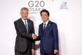 シンガポールのリー・シェンロン首相と握手を交わす安倍晋三元首相（2019年6月28日撮影）。(c)Ludovic MARIN / POOL / AFP