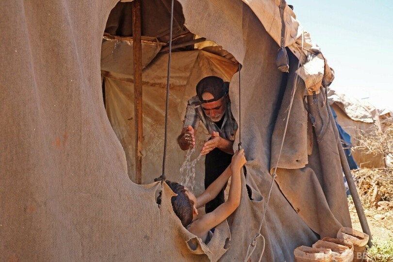 【今日の1枚】かけ水でわずかばかりの涼、難民キャンプ襲う熱波 シリア