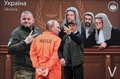 ウクライナの首都キーウに登場した、国際刑事裁判所の法廷に立つロシアのウラジーミル・プーチン大統領を描いたパネルの前で自撮りする男性（2023年5月11日撮影）。(c)Sergei SUPINSKY / AFP
