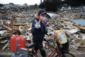 11日に発生した東北地方太平洋沖地震で被害を受けた東北沿岸の各地域では、17日も自衛隊員らによる救援活動が続いた。写真は、宮城県気仙沼市で、がれきの中でVサインを見せる人（2011年3月17日撮影）。(c)AFP/Nicolas ASFOURI