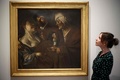 英ロンドンのコートールド美術館の「Art and Artifice: Fakes from the Collection（アートと策略：コレクションの贋作）」展で贋作者ハン・ファン・メーヘレンが手掛け、ディルク・ファン・バビューレンの作品とうたわれていた作品を見る同館の職員（2023年6月16日撮影）。(c)HENRY NICHOLLS / AFP