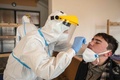 チェコ・西ボヘミア地方の新型ウイルス検査所で、個人用防護具（PPE）を身に着けて検体を採取する兵士（左、2021年3月3日撮影）。(c)Michal Cizek / AFP