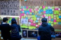 豪ブリスベンのクイーンズランド大学で、いわゆる「レノンウォール」にはられたメッセージを見る香港民主派デモの支持者ら（2019年8月9日撮影）。(c)Patrick HAMILTON / AFP