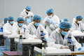 中国・江西省南昌市の工場で、防護服を着てマスクを縫製する従業員（2020年4月8日撮影、資料写真）。(c)STR / AFP