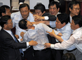 韓国国会で22日、与党ハンナラ党（Grand National Party、GNP）がメディア規制緩和法案を強行採決しようとしたため、与野党議員が国会で乱闘する騒ぎとなった。法案は可決されたが、十数人の負傷者が出た。写真は、与党議員らともみ合いになる野党議員（中央、2009年7月22日撮影）。(c)AFP/JUNG YEON-JE