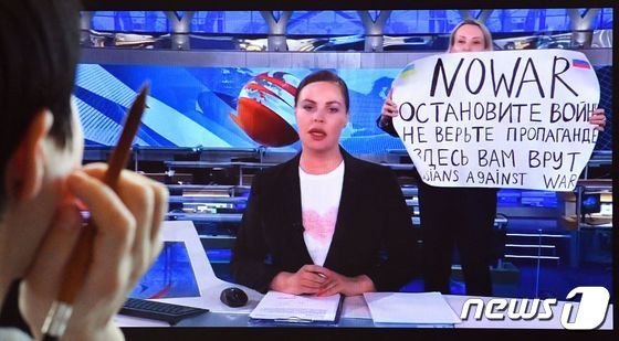 14日、ロシアの主要テレビ「第1チャンネル」で、ニュース番組の生放送中に女性社員が「戦争をやめて」などと大書された紙を掲げた(c)AFP=news1