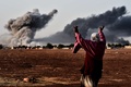 イスラム過激派組織「イスラム国（Islamic State、IS）」を標的とする米軍主導の空爆が行われたシリア北部アインアルアラブ（Ain al-Arab、クルド名：コバニ、Kobane）から立ち上る煙を、国境の反対側トルコ・シャンルウルファ（Sanliurfa）県の村ムルシトピナル（Mursitpinar）から見る女性（2014年10月13日撮影）。(c)AFP/ARIS MESSINIS