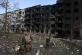 ロシア軍の攻撃を受けたウクライナ東部ドネツク州オチェレティネ村を歩く警察官（2024年4月15日撮影）。(c)Anatolii STEPANOV / AFP
