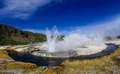 米イエローストーン国立公園（Yellowstone National Park）内のブラックサンドベイスン（Black Sand Basin）を流れるアイアン・クリーク（Iron Creek、手前の川）と間欠泉クリフ・ガイザー（Cliff Geyser、中央奥）。高さ30～40フィート（約9～12メートル）まで熱湯や水蒸気を吹き上げるクリフ・ガイザーの周囲には、噴き出した「湯の花」が固まって壁のように盛り上がっている。

1872年に米国初の国立公園として設立されたイエローストーンには、1万を超える間欠泉や泥間欠泉、蒸気孔、温泉がある。ワイオミング（Wyoming）、モンタナ（Montana）、アイダホ（Idaho）の3州にまたがり、公園名はイエローストーン川（Yellowstone River）にちなんでいる（2012年10月8日撮影）。(c)AFP/Karen BLEIER