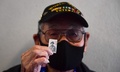第2次世界大戦中に欧州戦線で戦った日系2世で構成された米陸軍第100歩兵大隊と第442連隊をたたえる新切手を手にする、元米軍兵士のラルフ・マツモトさん。米カリフォルニア州ロサンゼルスの全米日系人博物館で（2021年6月4日撮影）。(c)Frederic J. BROWN / AFP