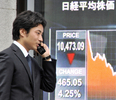 都内で、株価を示す電光ボードの前を通る男性（2008年10月6日撮影）。(c)AFP/Yoshikazu TSUNO