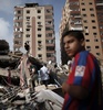 パレスチナ自治区ガザ地区（Gaza Strip）ガザ市（Gaza City）で、ミサイル着弾で倒壊した集合住宅のがれきの中から私物を拾い集める人々（2014年8月24日撮影）。(c)AFP/THOMAS COEX