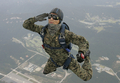韓国・鶏龍（Gyeryong）の陸海空軍本部で前月29日、1日に61年を迎える「国軍の日（Armed Forces Day）」に向けたリハーサルが行われた。1950年～53年の朝鮮戦争で、韓国は1953年、北朝鮮と休戦協定を結んだが、法的には戦争状態にある。

写真は、鶏龍の陸海空軍本部で実施された「国軍の日」に向けた軍事演習で、上空のヘリコプターからパラシュート降下しながら、カメラに向かって敬礼する韓国軍特殊部隊兵士（2009年9月29日撮影）。(c)AFP/JO YONG-HAK