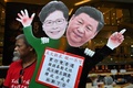 香港で、林鄭月娥（キャリー・ラム）行政長官と中国の習近平国家主席が描かれたプラカードを見せる民主派活動家（2019年12月18日撮影）。(c)Philip FONG / AFP