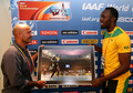 第14回世界陸上モスクワ大会（14th IAAF World Championships in Athletics Moscow）、男子100メートル決勝で撮影された写真を、撮影者のオリビエ・モラン（Olivier Morin、左）氏から受け取るウサイン・ボルト（Usain Bolt、2013年8月17日撮影）。(c)AFP/FRANCK FIFE