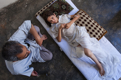 脚の切断手術を受けた息子を慰める父親、シリア