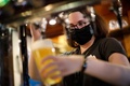 英ロンドン・ストラットフォードにあるパブで、マスク姿でビールを注ぐ従業員（2020年7月4日撮影）。(c)Tolga Akmen / AFP