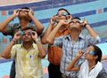 インド・アーメダバード（Ahmedabad）郊外で、日食グラスの使い方を習う人たち（2009年7月20日撮影）。(c)AFP/Sam PANTHAKY