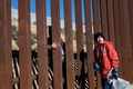 メキシコ・バハカリフォルニア州ティフアナで、母親の後に続いて泣きながら国境フェンスを越えようとする少年（2018年12月30日撮影）。(c)GUILLERMO ARIAS / AFP