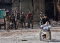 シリア・アレッポ東部のシャー地区で、政府軍の制圧後に市民が避難する中、負傷した女性の車いすを押す政府側部隊の戦闘員（2016年12月7日撮影）。(c)AFP/GEORGE OURFALIAN